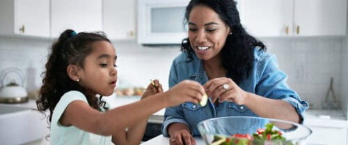 mother daughter making salad in kitchen