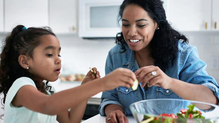 mother daughter making salad in kitchen