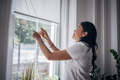 woman lowering blinds inside